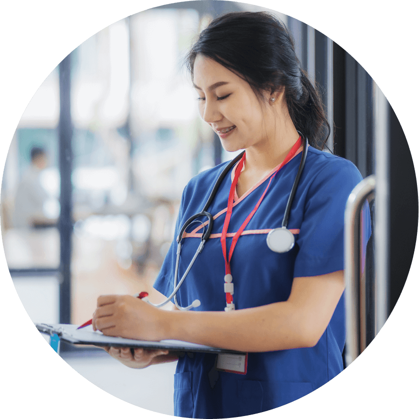 Actor portrayal of a female nurse in scrubs with a stethoscope around her neck writing on a clipboard